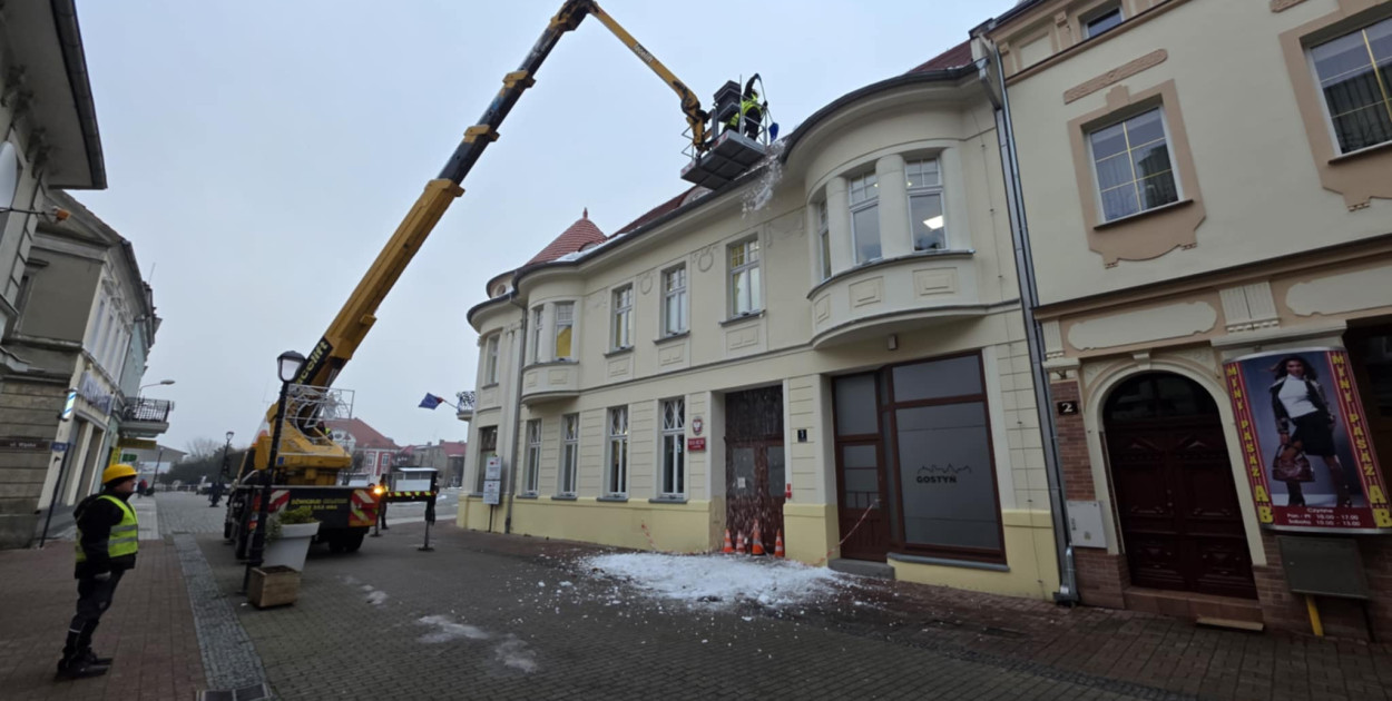 Usuwanie śniegu z dachu miejskiej kamienicy w Gostyniu